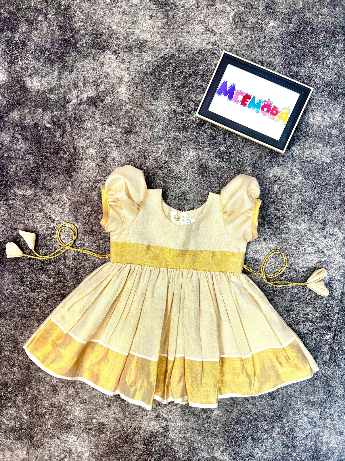 Girl wearing cream Kasavu Onam frock with gold zari border, front view